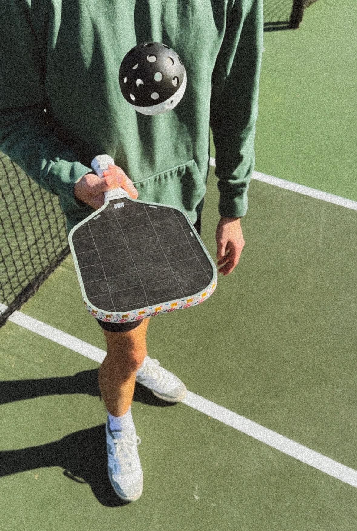 Spieler hält einen Pickleball-Schläger, der Ball schwebt in der Luft